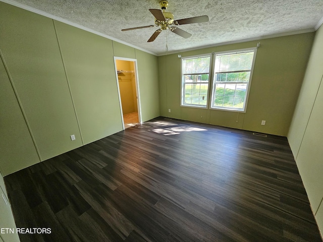 spare room with crown molding, dark wood-type flooring, and a textured ceiling