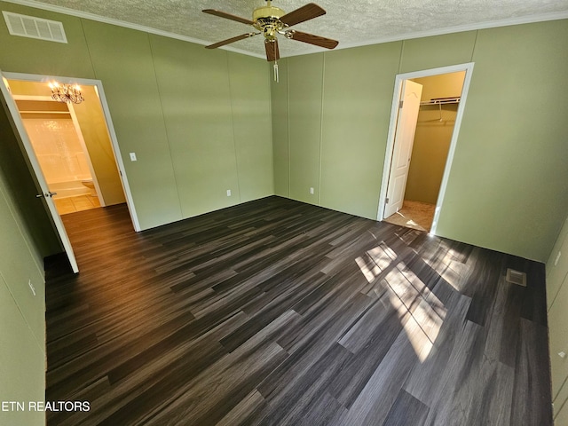 unfurnished bedroom featuring a spacious closet, a textured ceiling, dark hardwood / wood-style flooring, ceiling fan with notable chandelier, and a closet