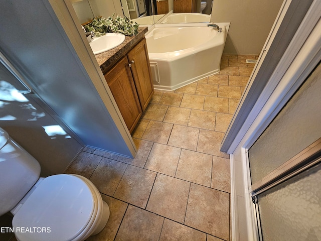 bathroom with tile patterned flooring, vanity, a tub, and toilet