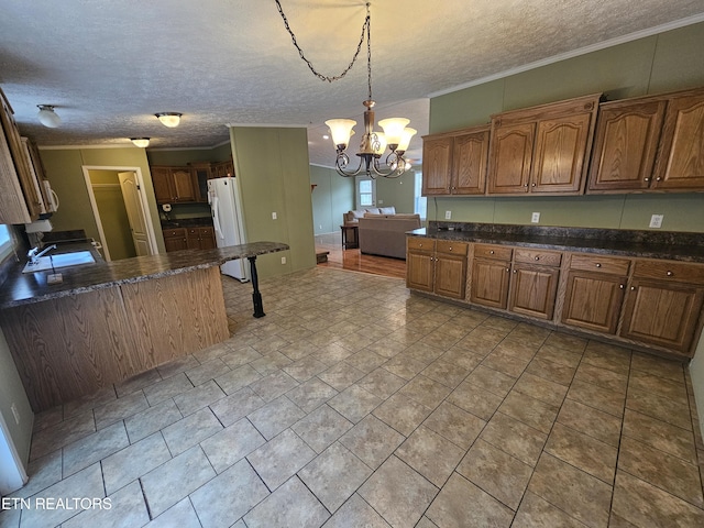 kitchen featuring sink, an inviting chandelier, hanging light fixtures, a textured ceiling, and white fridge