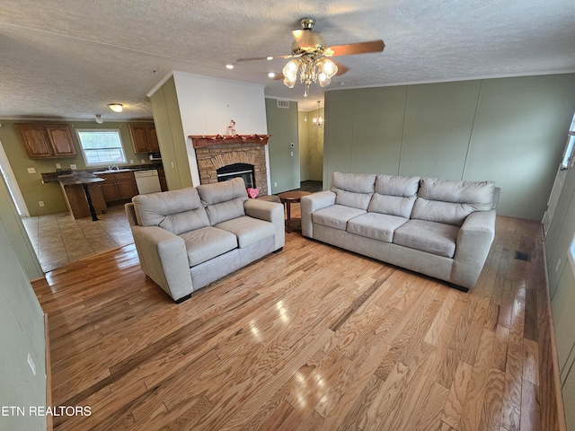 living room featuring sink, a fireplace, a textured ceiling, and light hardwood / wood-style floors