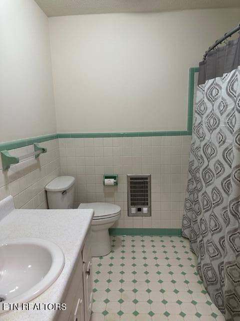 bathroom featuring vanity, tile walls, toilet, and heating unit