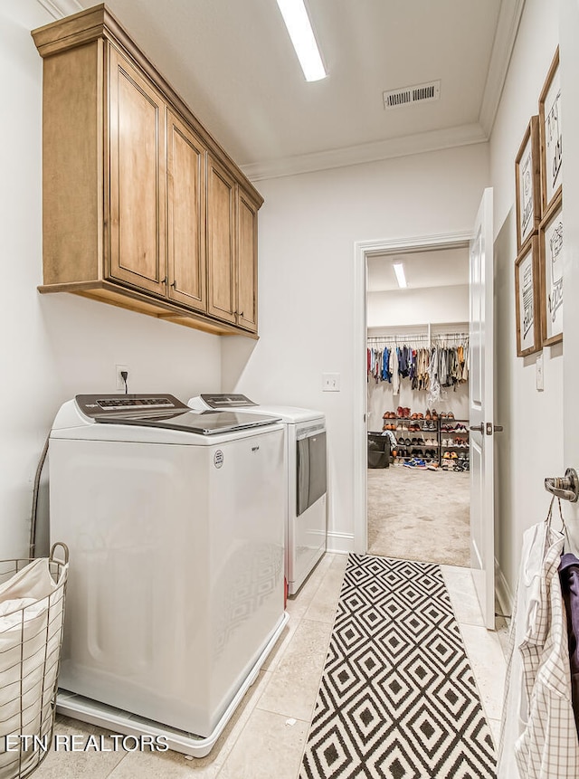 washroom with ornamental molding, light carpet, washer and dryer, and cabinets