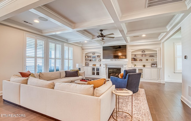 living room with ornamental molding, built in features, dark hardwood / wood-style flooring, and a high end fireplace