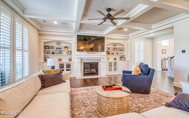 living room featuring built in shelves, beamed ceiling, a high end fireplace, dark wood-type flooring, and coffered ceiling