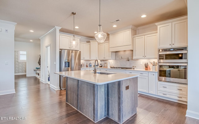 kitchen with dark wood-type flooring, decorative light fixtures, appliances with stainless steel finishes, and sink