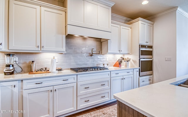 kitchen with ornamental molding, tasteful backsplash, white cabinetry, appliances with stainless steel finishes, and dark hardwood / wood-style floors