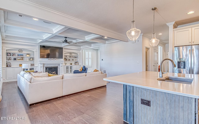 kitchen featuring light hardwood / wood-style floors, decorative light fixtures, a kitchen island with sink, and stainless steel fridge