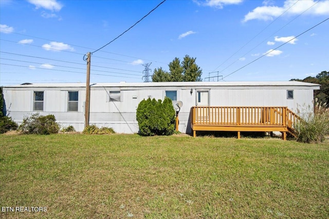 rear view of property featuring a wooden deck and a lawn