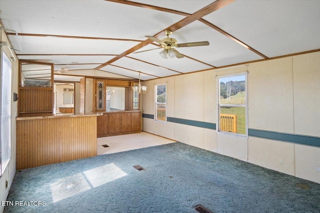 empty room with ceiling fan, vaulted ceiling, wooden walls, and light carpet