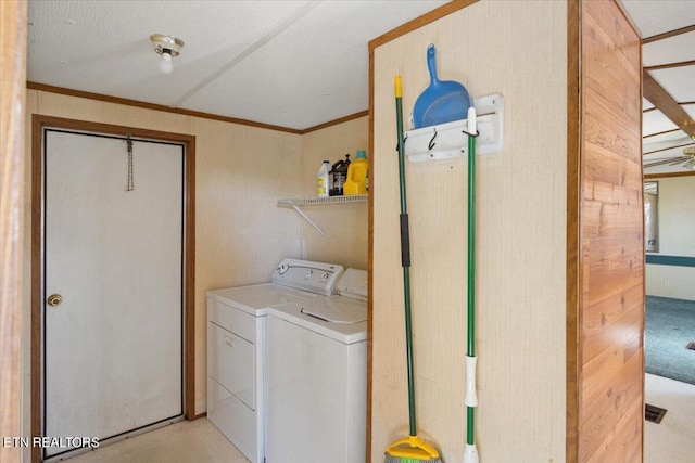 laundry area featuring a textured ceiling, ornamental molding, and washing machine and clothes dryer