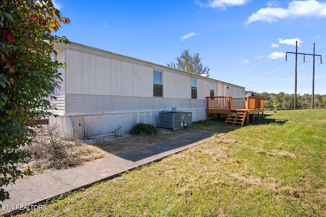 view of side of home featuring central AC, a lawn, and a wooden deck