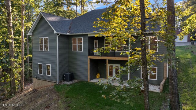 rear view of property featuring a yard, cooling unit, and a balcony