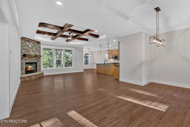 unfurnished living room with dark wood-type flooring, sink, a fireplace, coffered ceiling, and beam ceiling