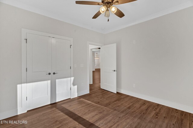 unfurnished bedroom featuring ceiling fan, a closet, dark hardwood / wood-style floors, and ornamental molding