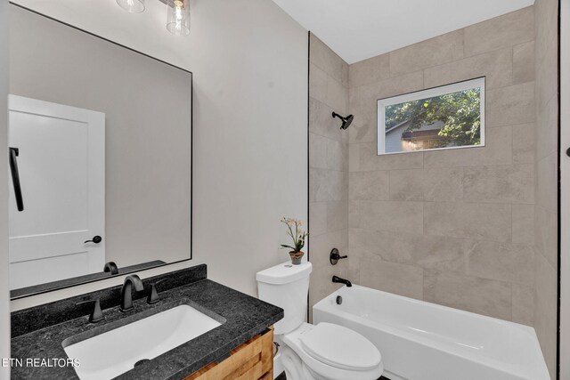 full bathroom featuring tiled shower / bath, vanity, and toilet