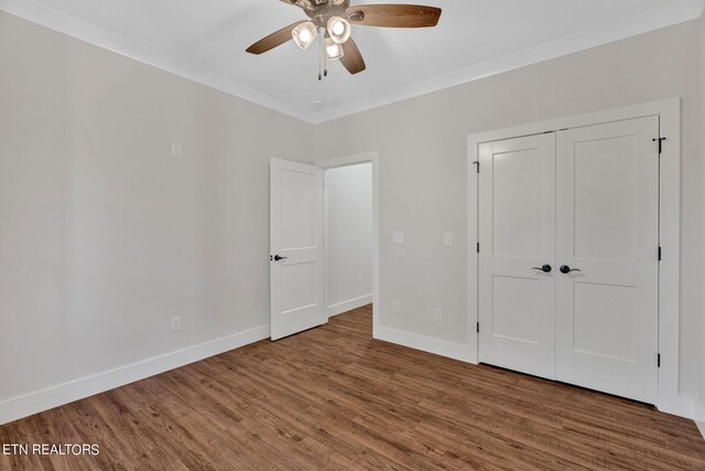 unfurnished bedroom with ceiling fan, a closet, ornamental molding, and wood-type flooring