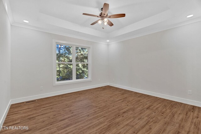 unfurnished room featuring ornamental molding, a tray ceiling, hardwood / wood-style floors, and ceiling fan