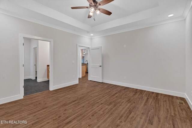 unfurnished bedroom featuring a raised ceiling, dark hardwood / wood-style flooring, and ceiling fan