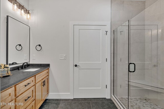 bathroom featuring tile patterned floors, a shower with door, and vanity