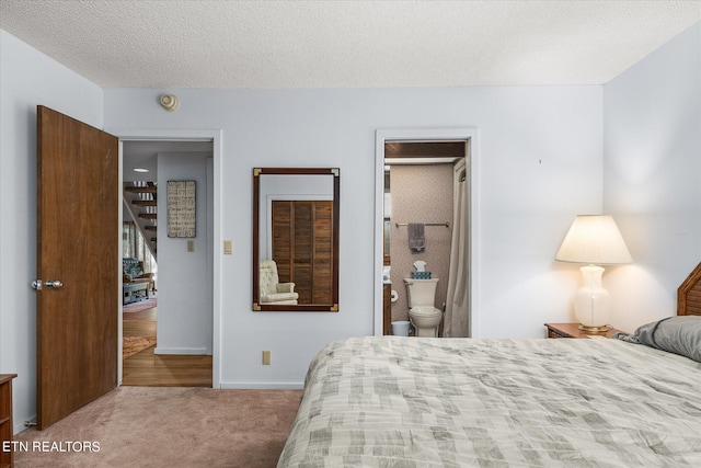 carpeted bedroom with ensuite bath and a textured ceiling