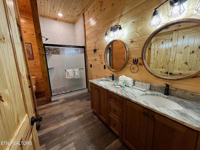 bathroom with an enclosed shower, wooden walls, vanity, and wood-type flooring