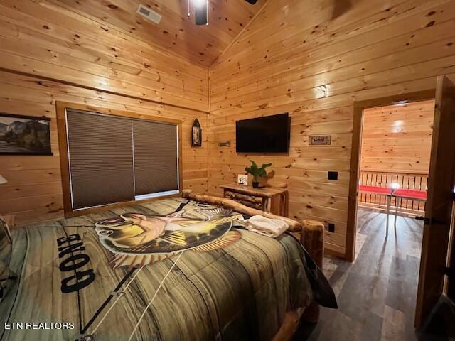 bedroom featuring lofted ceiling, hardwood / wood-style floors, and wooden walls