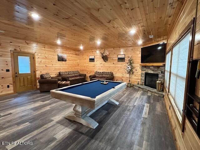 rec room with wooden ceiling, dark hardwood / wood-style flooring, wooden walls, and a stone fireplace