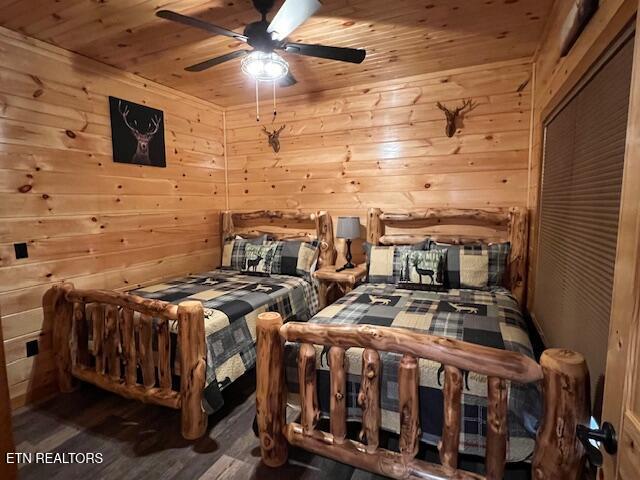 bedroom featuring ceiling fan, wood walls, wooden ceiling, and wood-type flooring