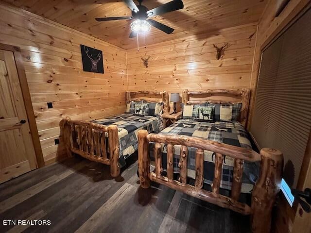 bedroom featuring ceiling fan, wood ceiling, wood walls, and dark wood-type flooring