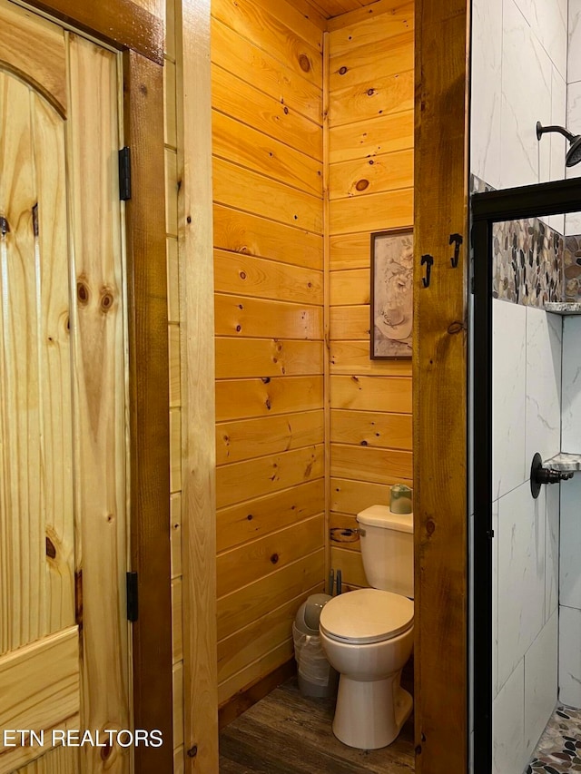 bathroom with wood walls, hardwood / wood-style floors, and toilet