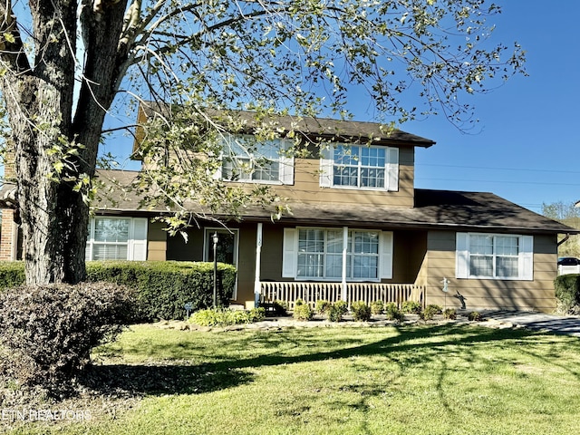 traditional home featuring covered porch, roof with shingles, and a front lawn