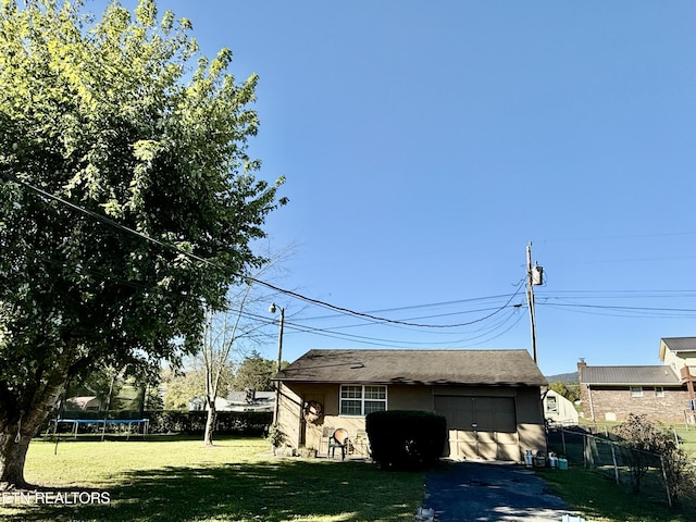 garage with a trampoline, fence, and driveway