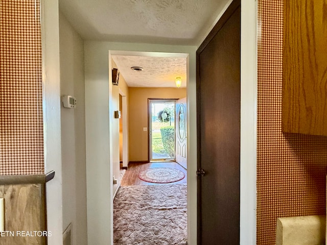 doorway featuring light wood-type flooring and a textured ceiling