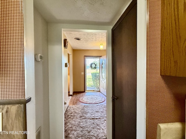 hall featuring a textured ceiling