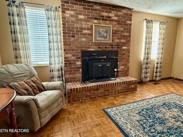 living area featuring a textured ceiling, a fireplace, and light parquet floors