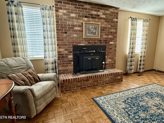 living area featuring baseboards, a brick fireplace, and a textured ceiling