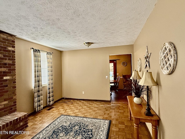 interior space with a textured ceiling, visible vents, and baseboards