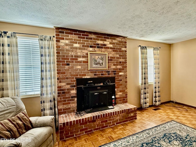 living room with a brick fireplace, a textured ceiling, and parquet floors