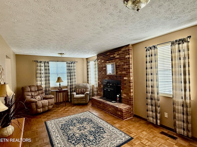 living room with a brick fireplace, a textured ceiling, and parquet flooring