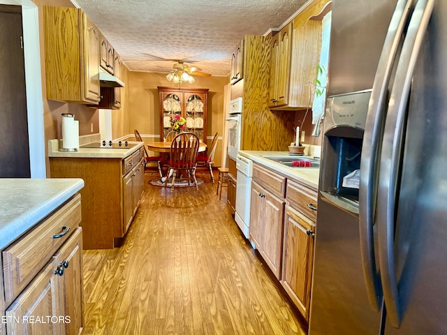 kitchen featuring ceiling fan, white appliances, light hardwood / wood-style flooring, sink, and a textured ceiling