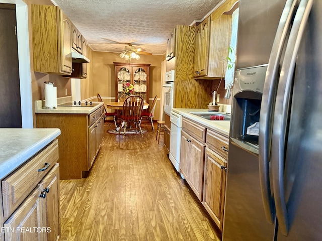kitchen featuring light wood-style floors, light countertops, a textured ceiling, and white appliances