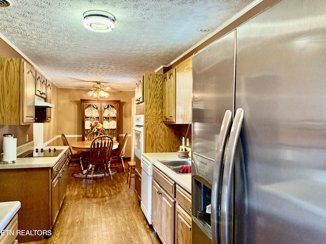 kitchen with a textured ceiling, wood finished floors, light countertops, under cabinet range hood, and white appliances
