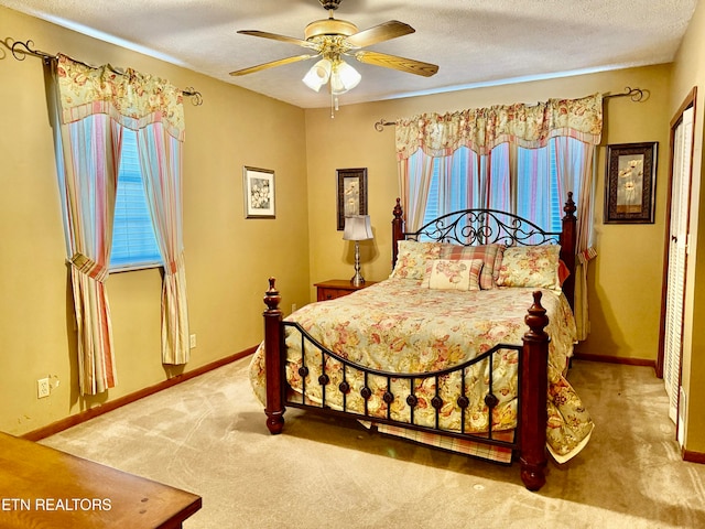 carpeted bedroom featuring ceiling fan and a textured ceiling