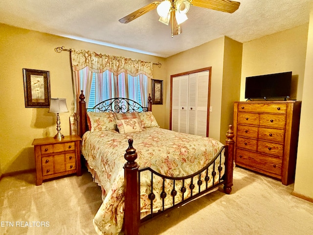 carpeted bedroom featuring ceiling fan, a closet, and a textured ceiling