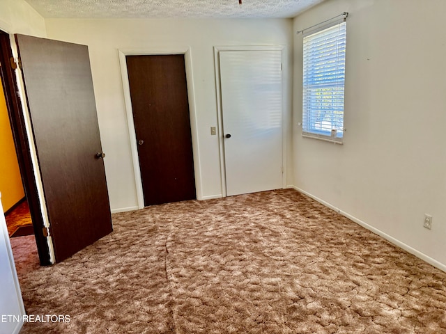 unfurnished bedroom with a textured ceiling and carpet flooring