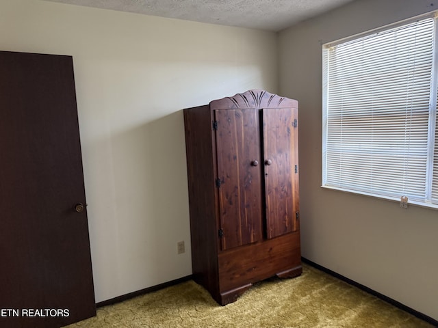unfurnished bedroom with baseboards, a textured ceiling, and light carpet