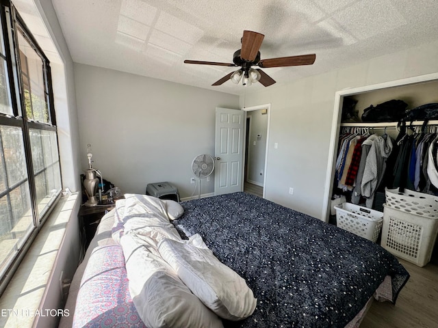 bedroom with a ceiling fan, a closet, a textured ceiling, and wood finished floors