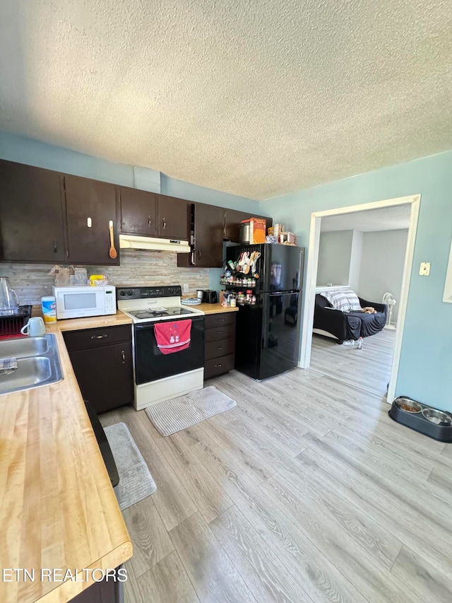 kitchen with white microwave, under cabinet range hood, a sink, electric stove, and freestanding refrigerator