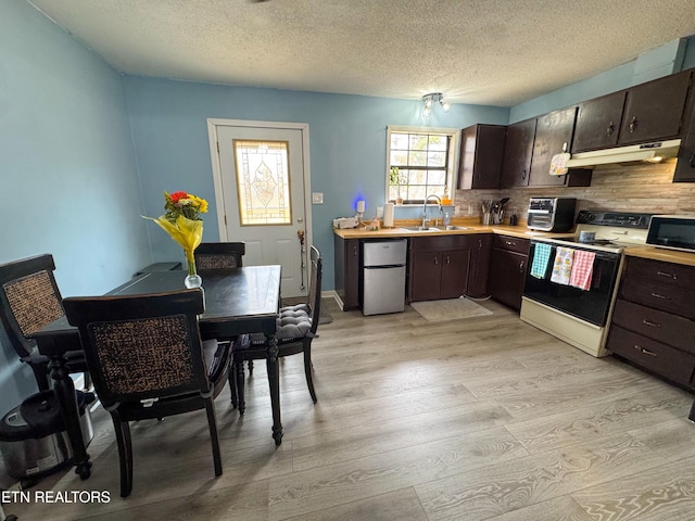 kitchen with white electric range oven, light countertops, a sink, black microwave, and fridge